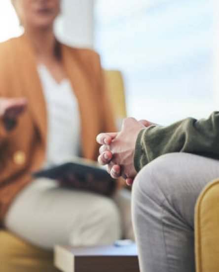 Man, hands and listening for therapy, sofa or advice from woman for mental health, psychology or care. Psychiatrist, patient and frustrated in clinic, session or couch for help, anxiety or depression